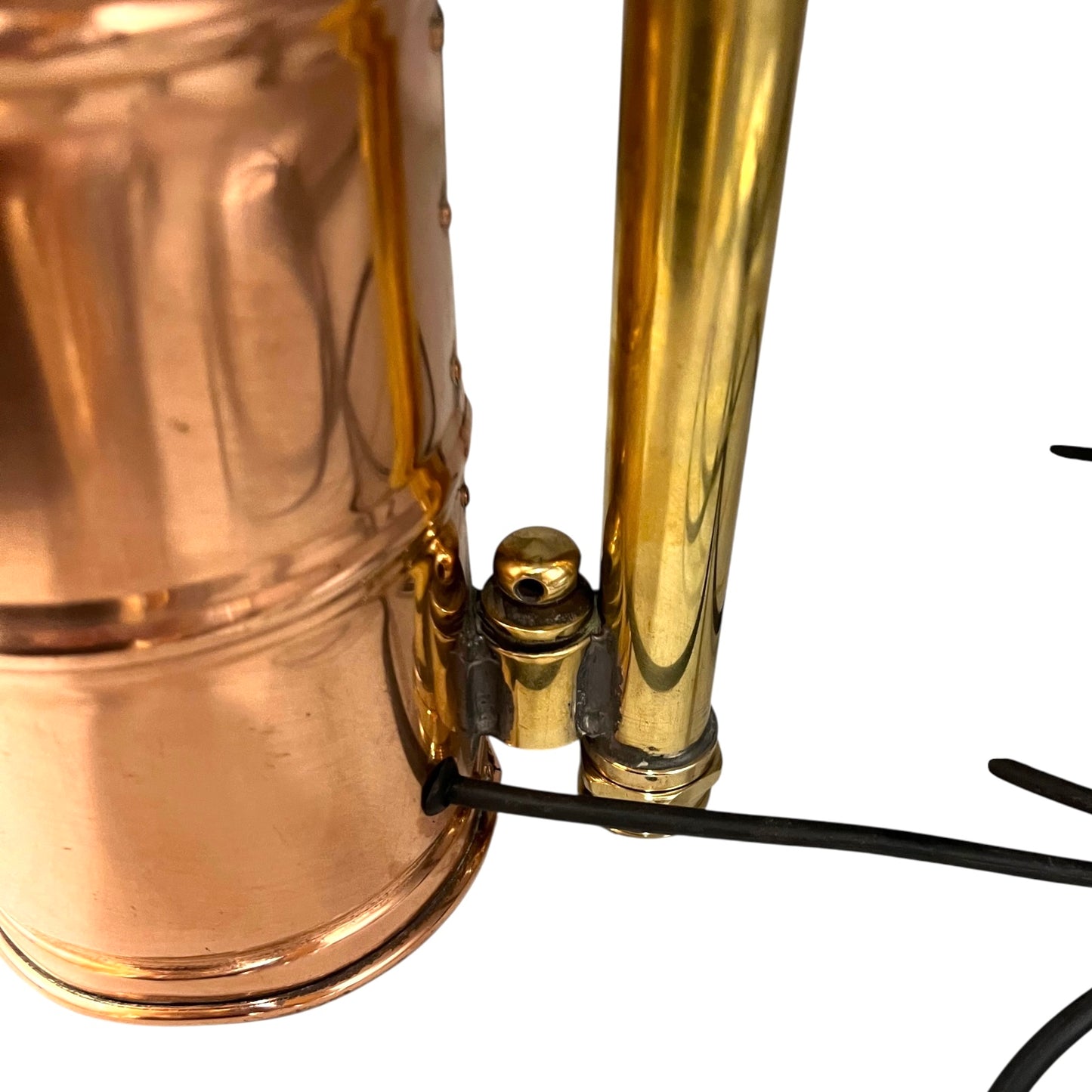 Close-up of a copper and brass lamp with visible wiring on a white background