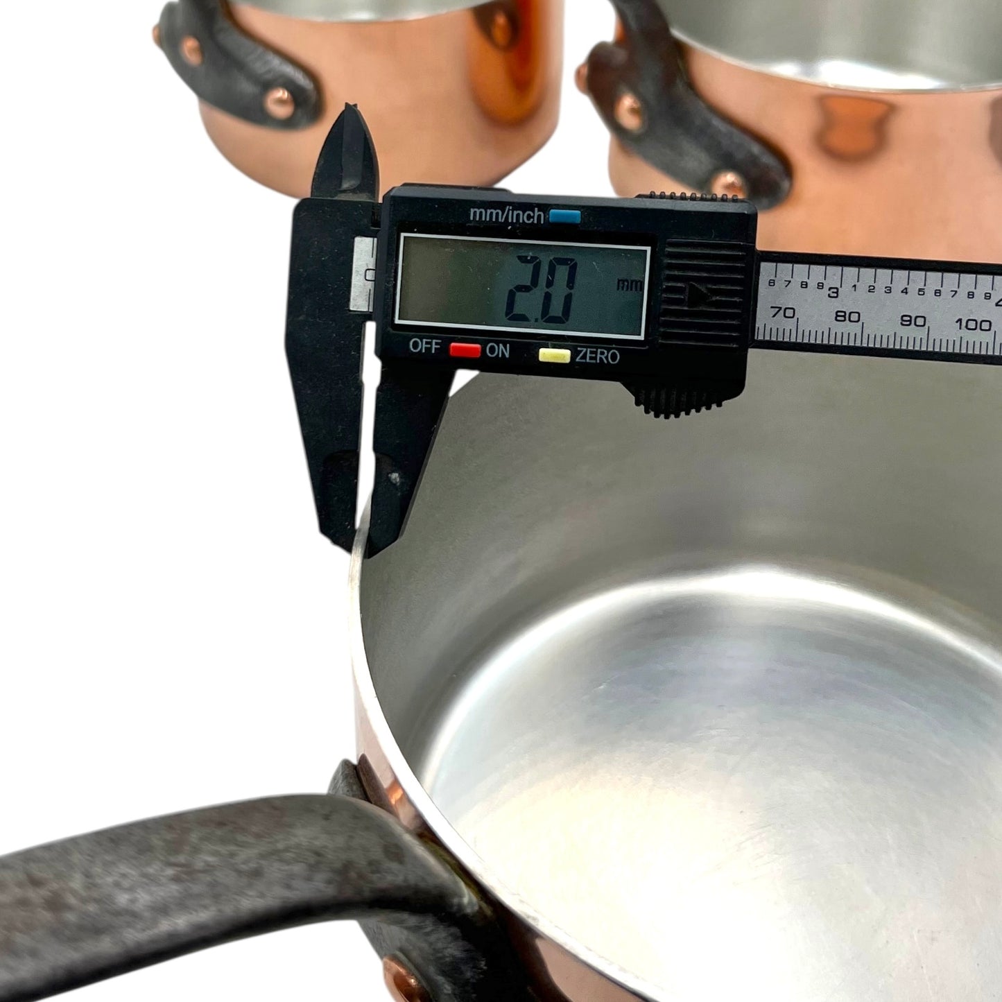 Digital caliper measuring the depth of a metallic pot.