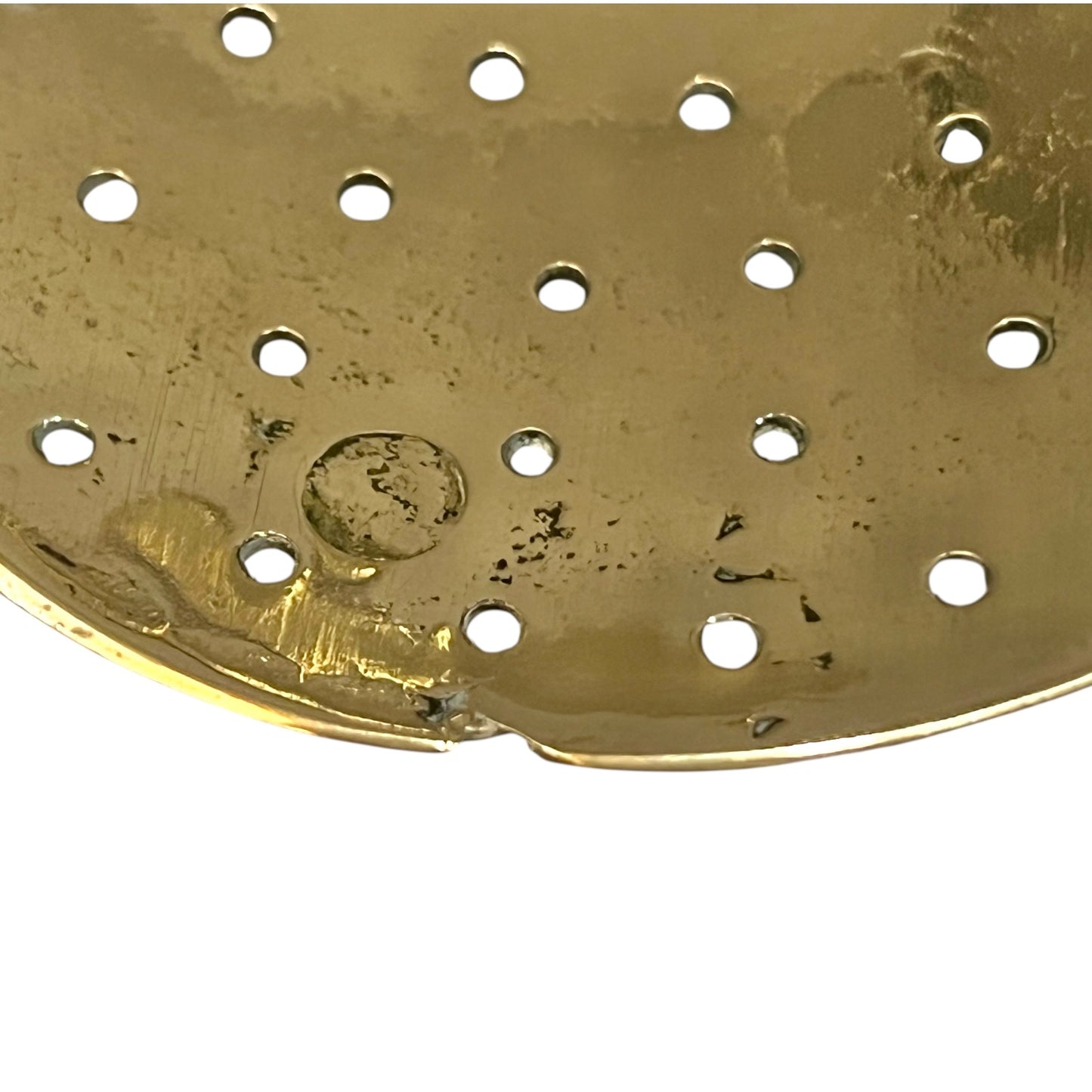 Gold-colored metal strainer with holes on a white background