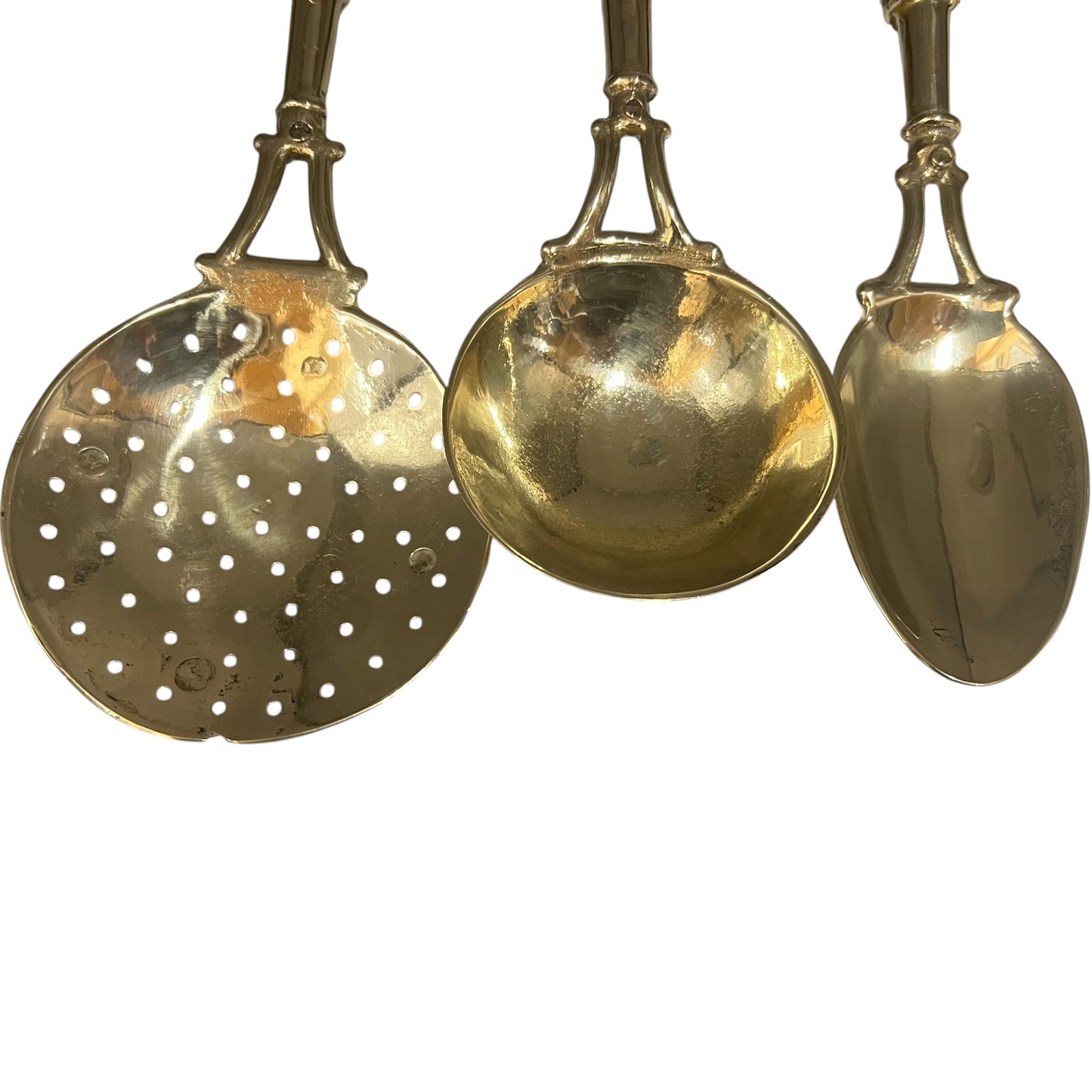 Three gold-colored spoons with different designs on a white background