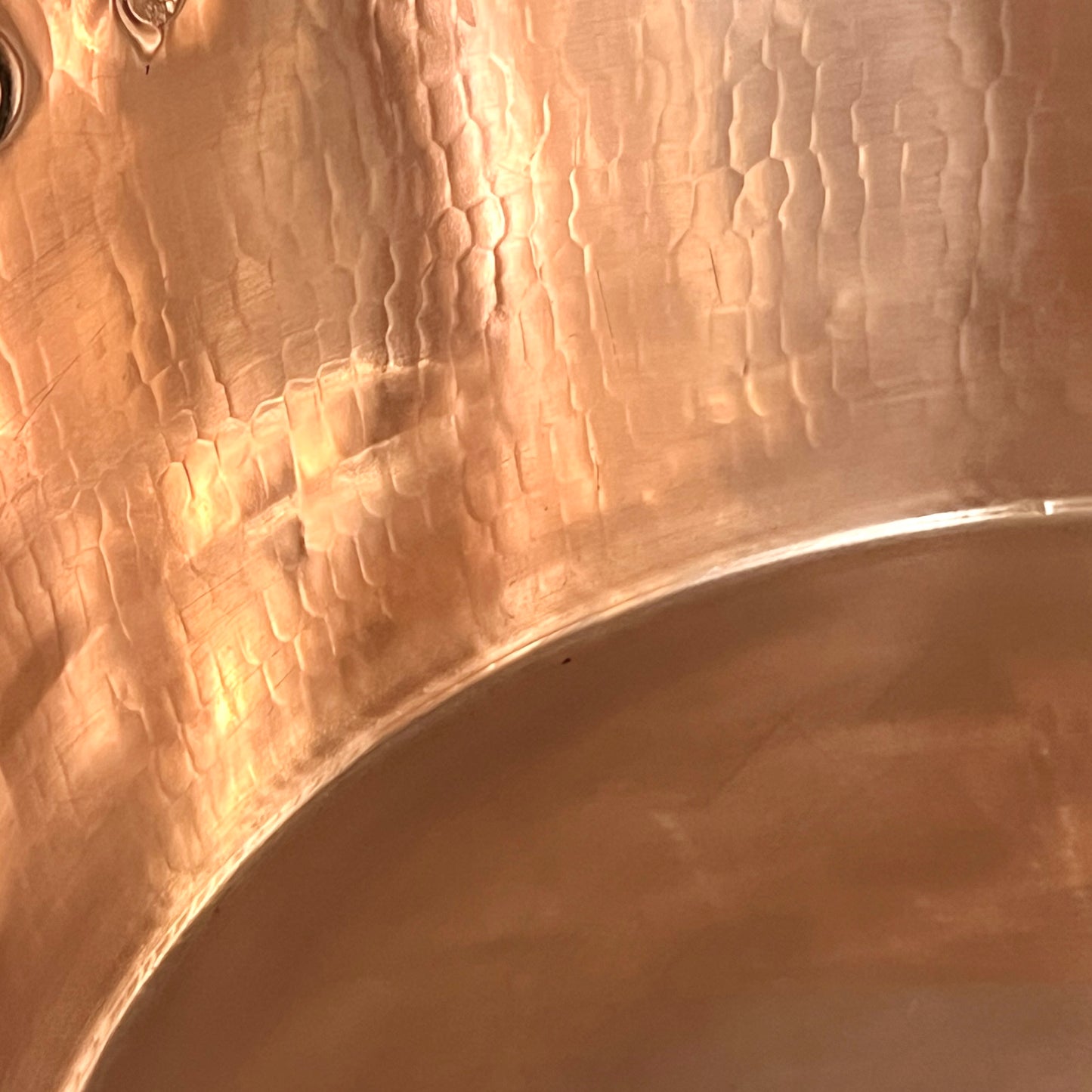 Close-up of copper sink with brass pop up waste on a white background