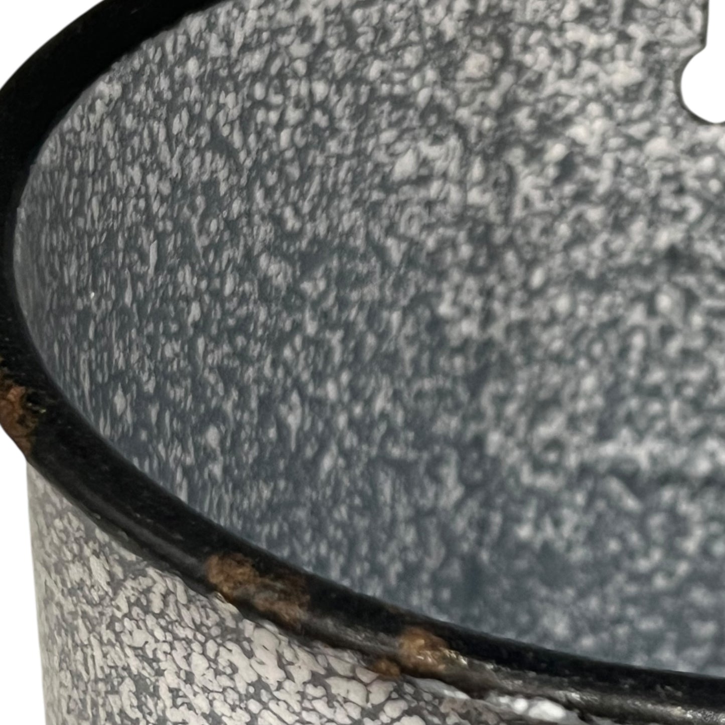 close up of vintage French grey and white speckled irrigator with a spout and a handle showing wear and tear on a white background