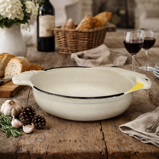 White ceramic dish with goose head decoration on a wooden table with bread, wine, and flowers.