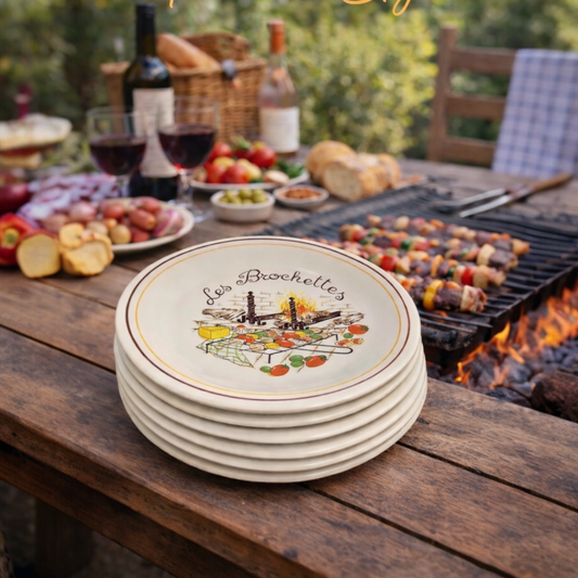 Stack of plates with 'Les Brochelles' design on a wooden table with outdoor setting
