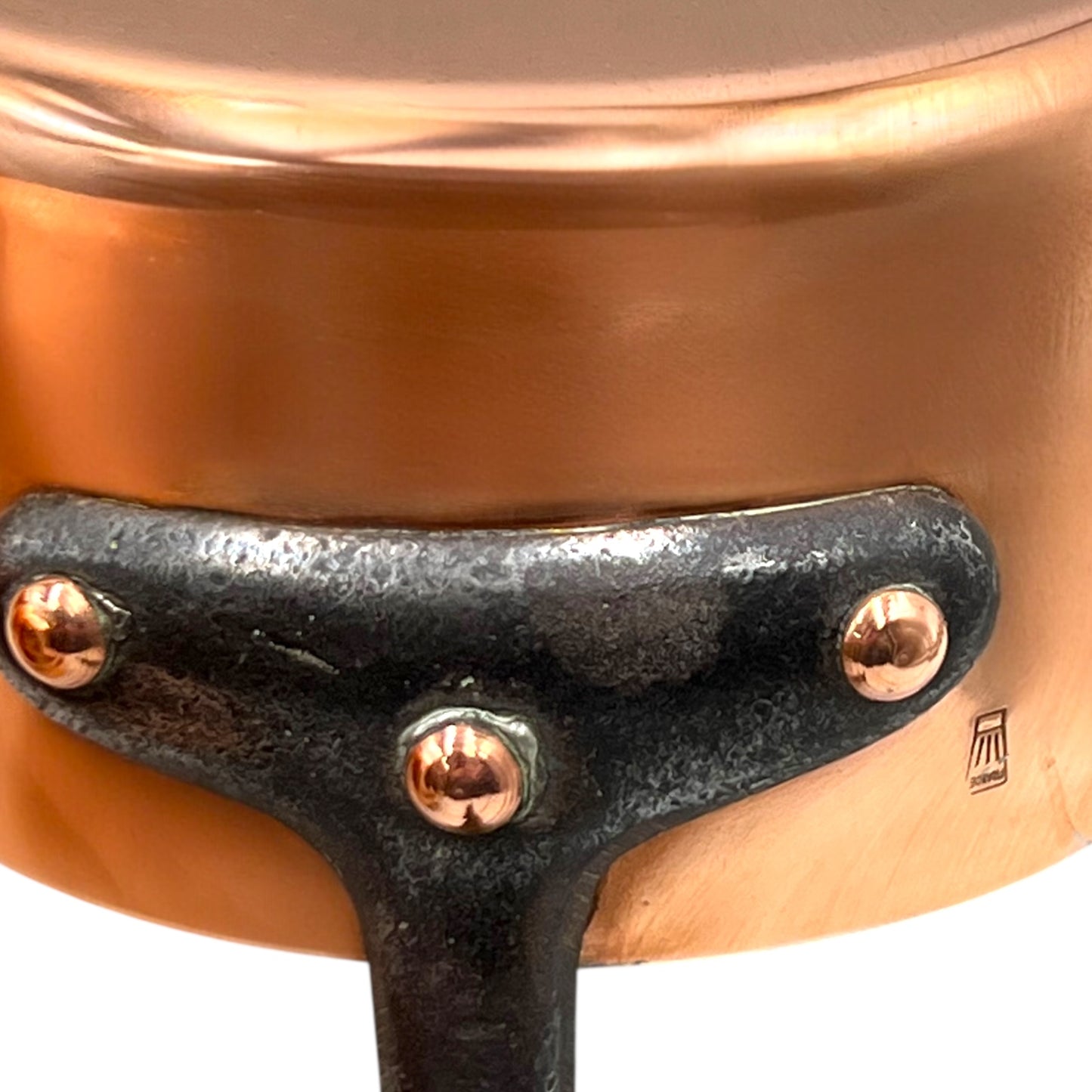 Close-up of a copper pot with a black handle and visible brand logo.