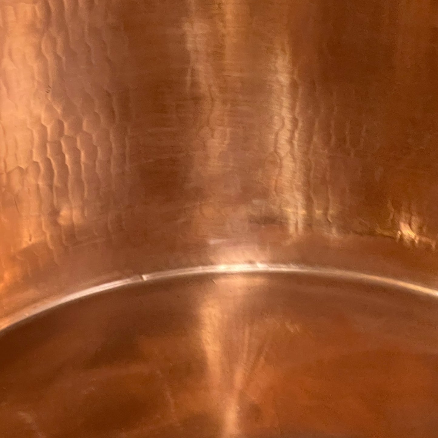 Close-up of copper sink with brass pop up waste on a white background