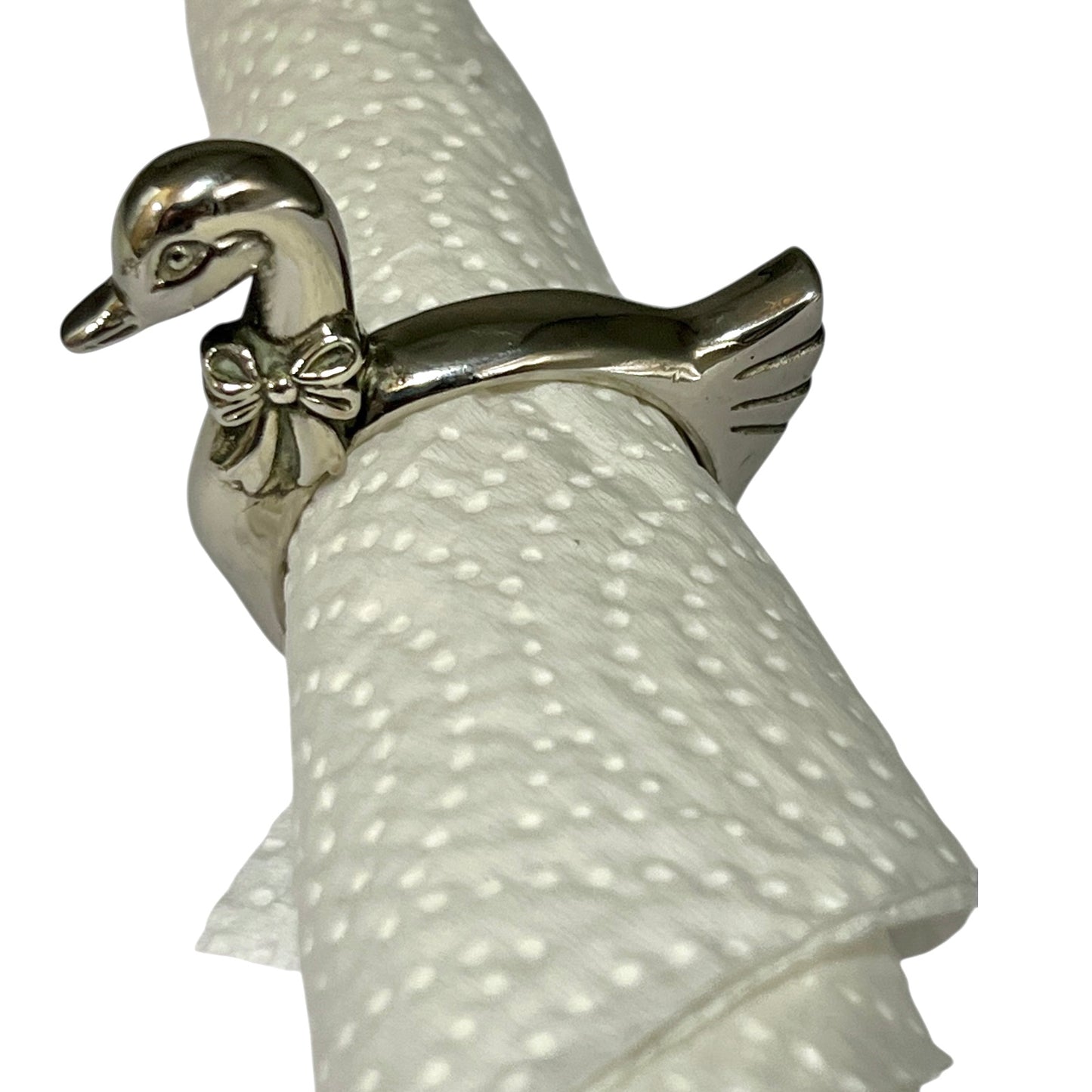 Close-up of a swan shaped silver plated napkin ring with a paper serviette on a white background