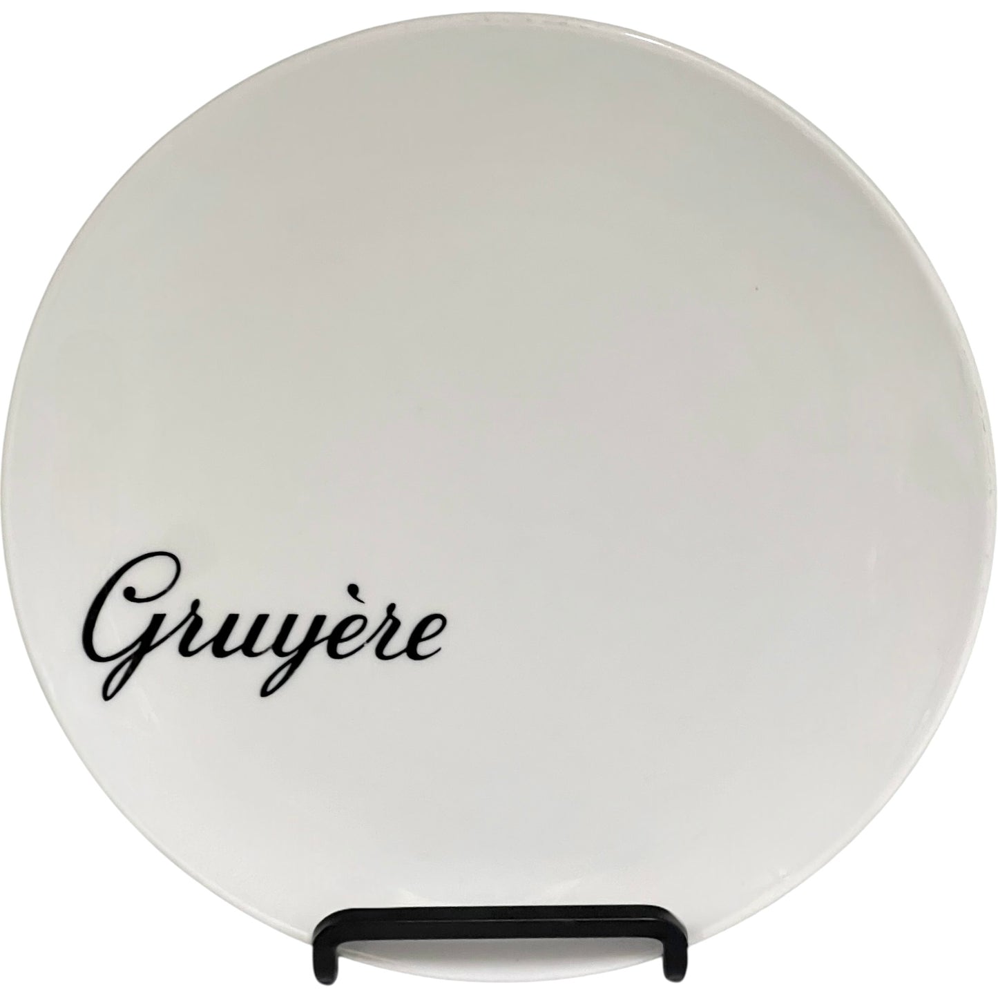 Round white cheese plate with 'Gruyère' text on a stand