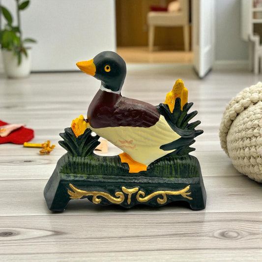 Cast iron duck doorstop on a decorative stand with a blurred background for sale from All Things French Store