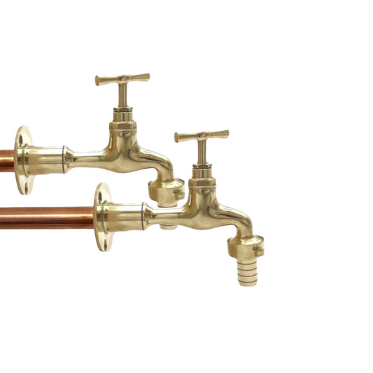 A pair of brass vintage style wall mounted taps with copper pipework, isolated on a white background for sale by All Things French Store.
