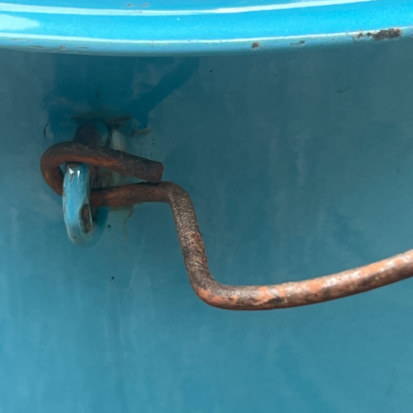 Close up of blue metal bucket with a wooden handle on a white background