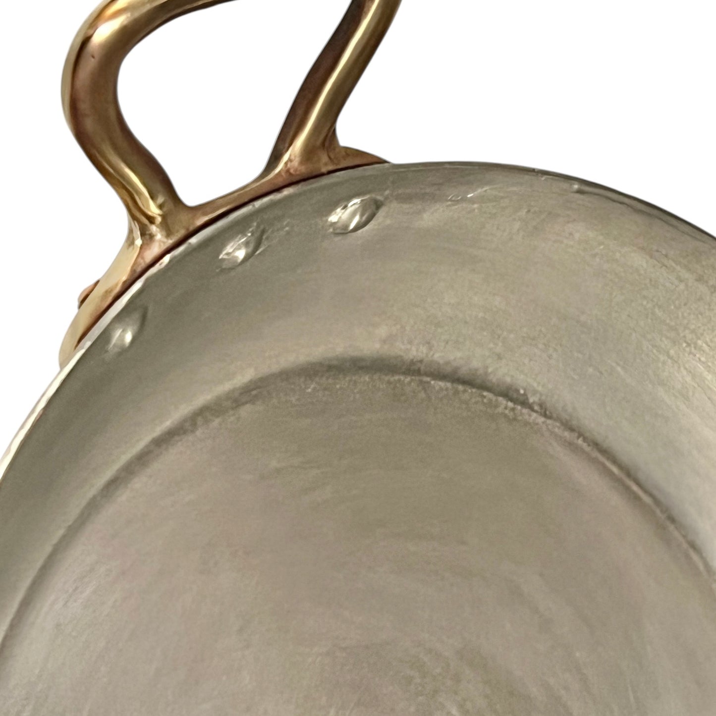 close up of French copper round gratin pan with brass handles and tin lining on a white background
