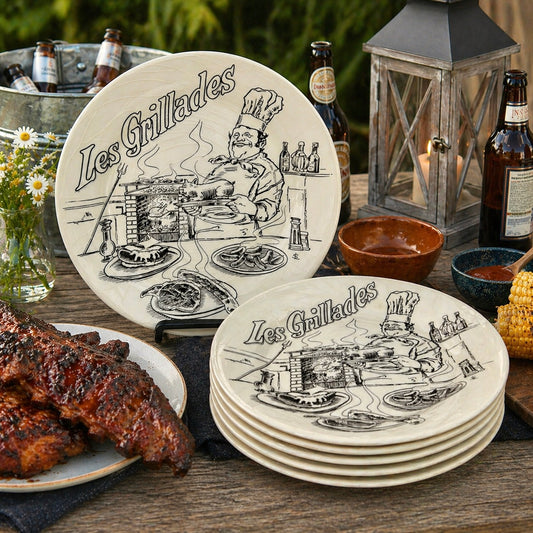 Set of 'Les Grillades' plates with a graphic design of a chef and grill, placed on a table with food and drinks.