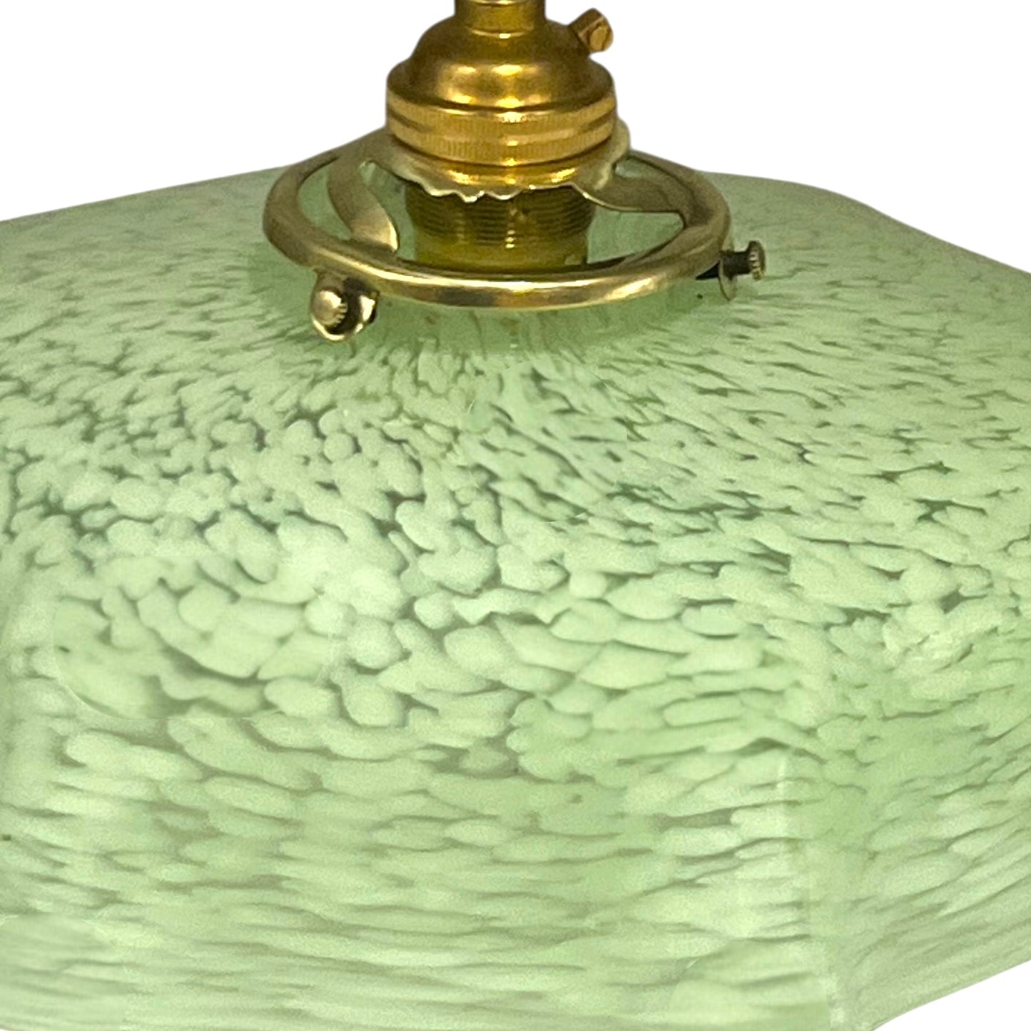 Close-up of a green textured lampshade with a brass fitting on a white background