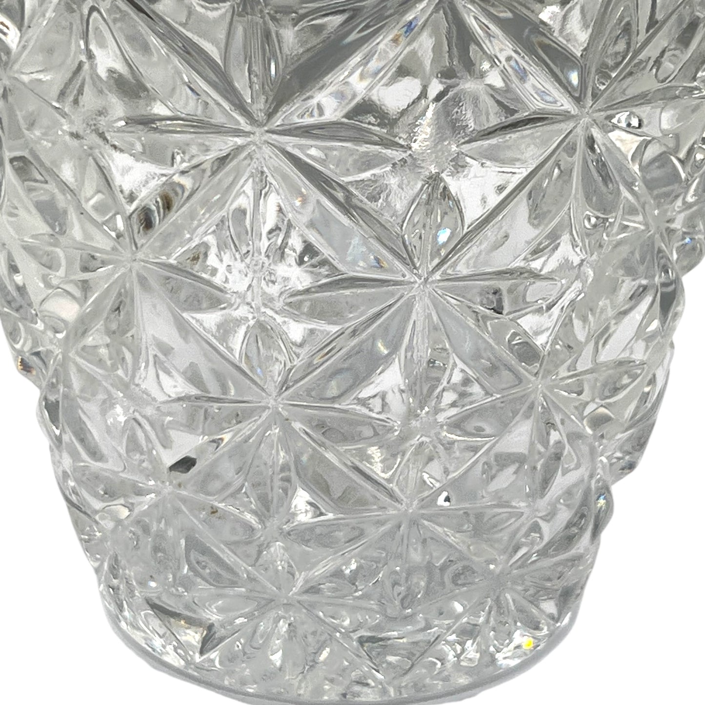 Close up of French cut glass ice bucket with textured design and metal handle on a white background