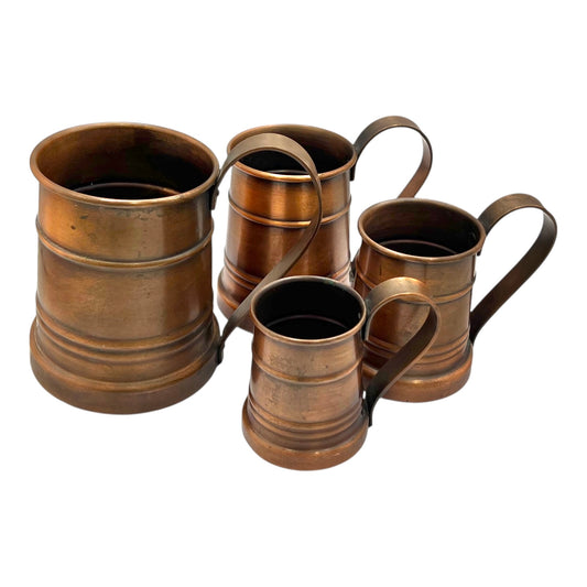 Set of four copper mugs with handles on a white background