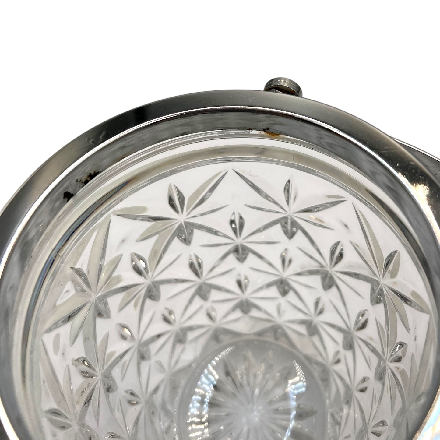 Close up of French cut glass ice bucket with textured design and metal handle on a white background