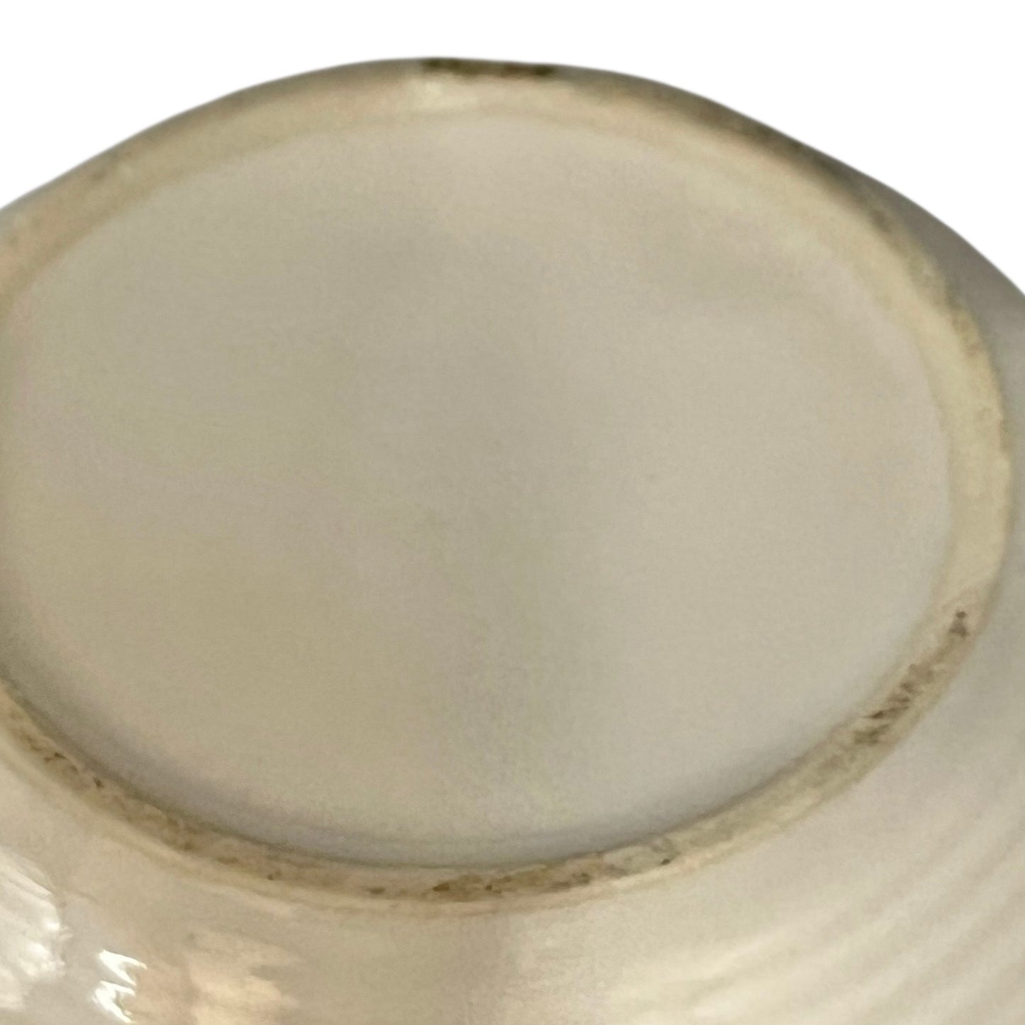 Close-up of a ceramic bowl base with a smooth, light-coloured glaze on a white background