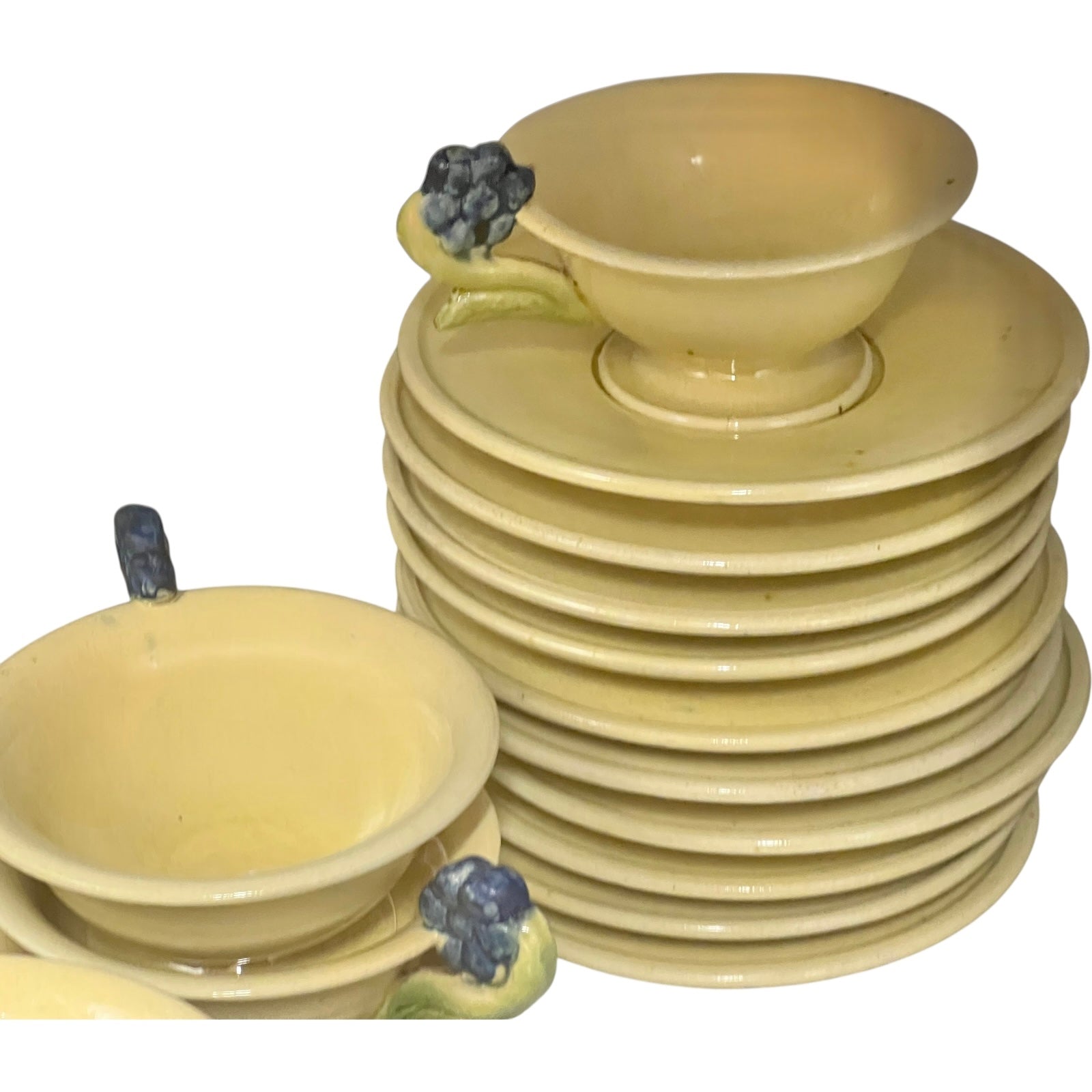 Stack of ceramic cups and plates with decorative handles on a white background