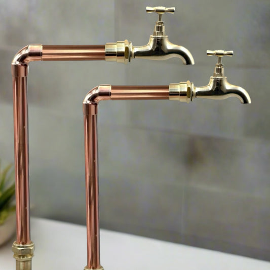 Vintage-style copper and brass faucet taps on a neutral background