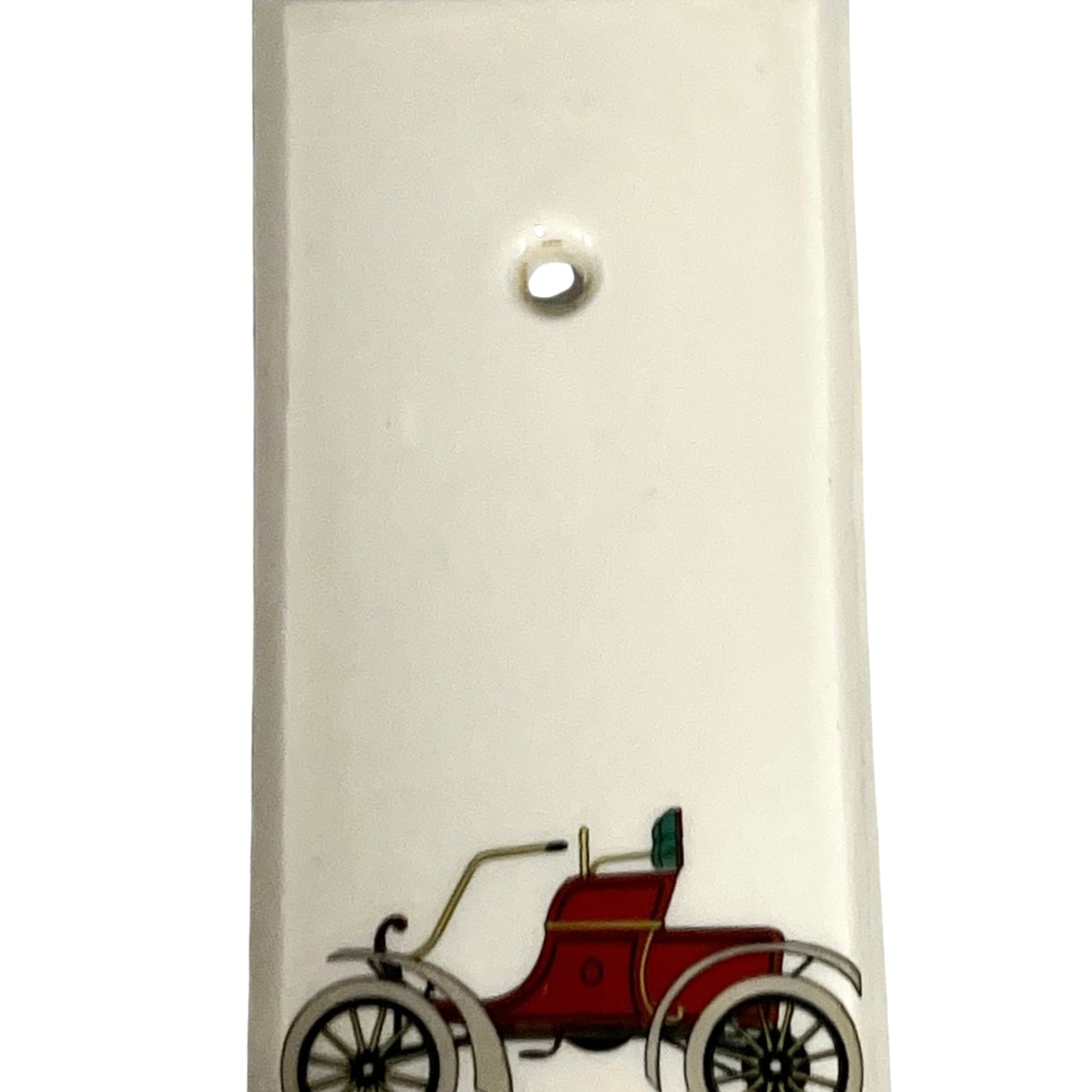 Close up of fingerplate with vintage car illustrations on a white background