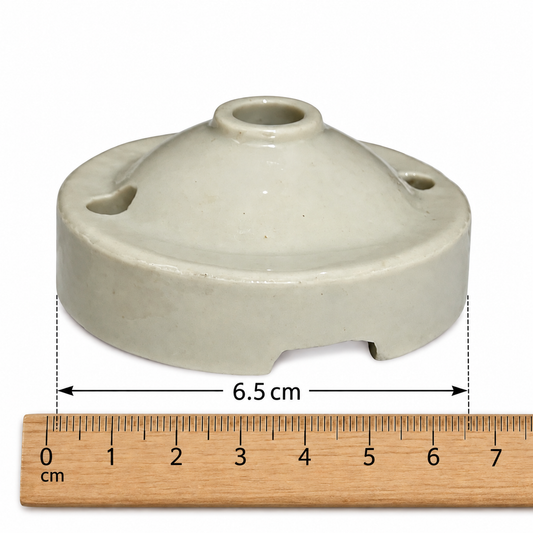 A small ceramic ceiling rose with a rounded, dome-shaped top and side holes, shown above a wooden ruler marked in centimetres to indicate its 6.5 cm width.