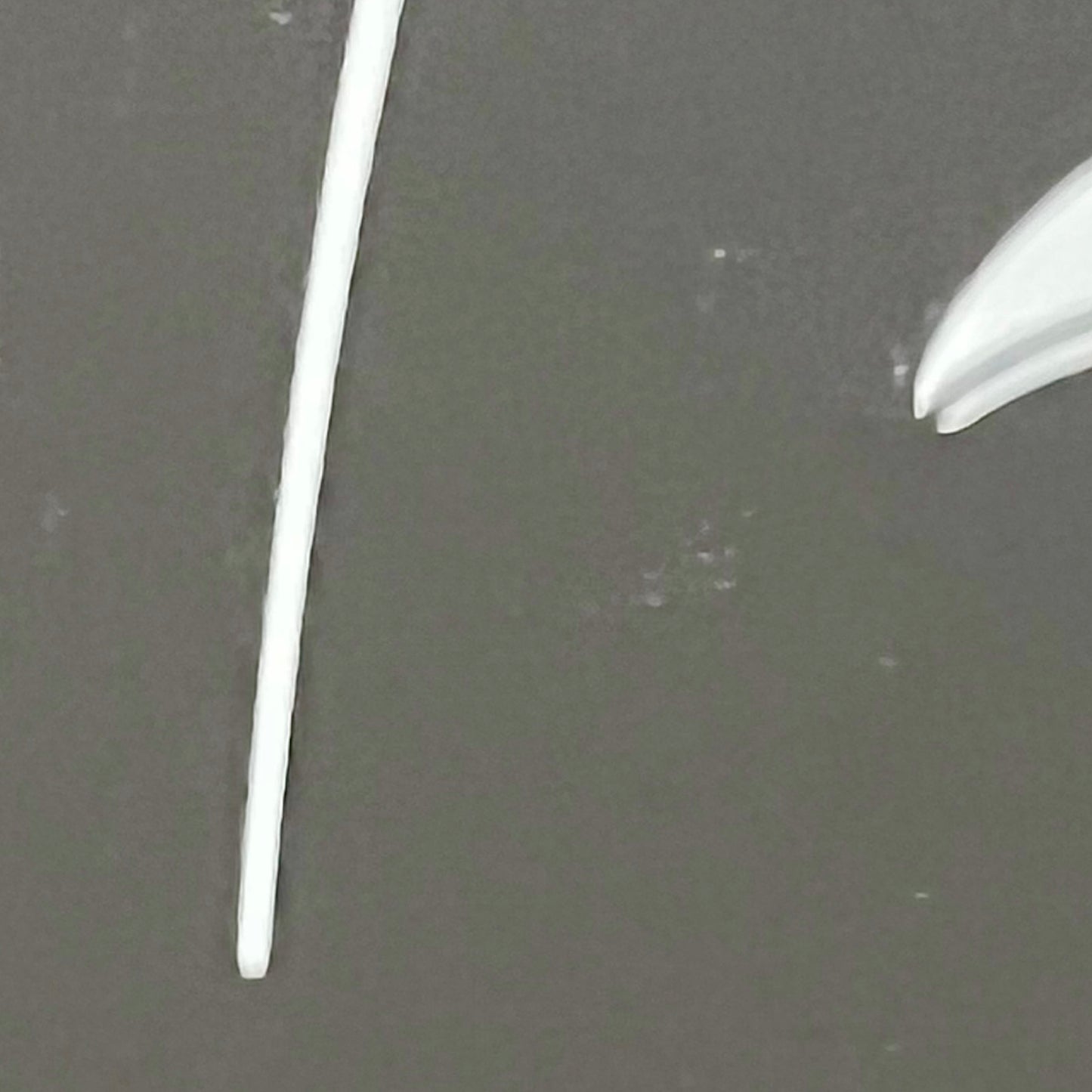 Two white plastic straws on a gray background