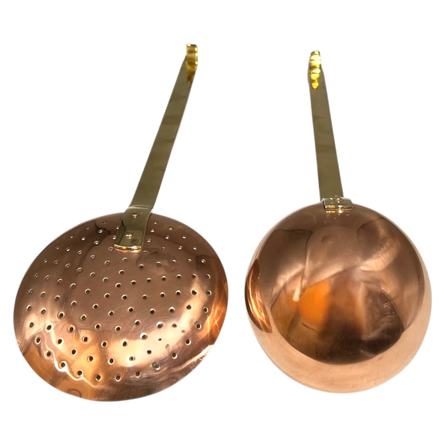 Set of 2 French copper utensils with long brass handles, includes a straining spoon and a ladle on a white background