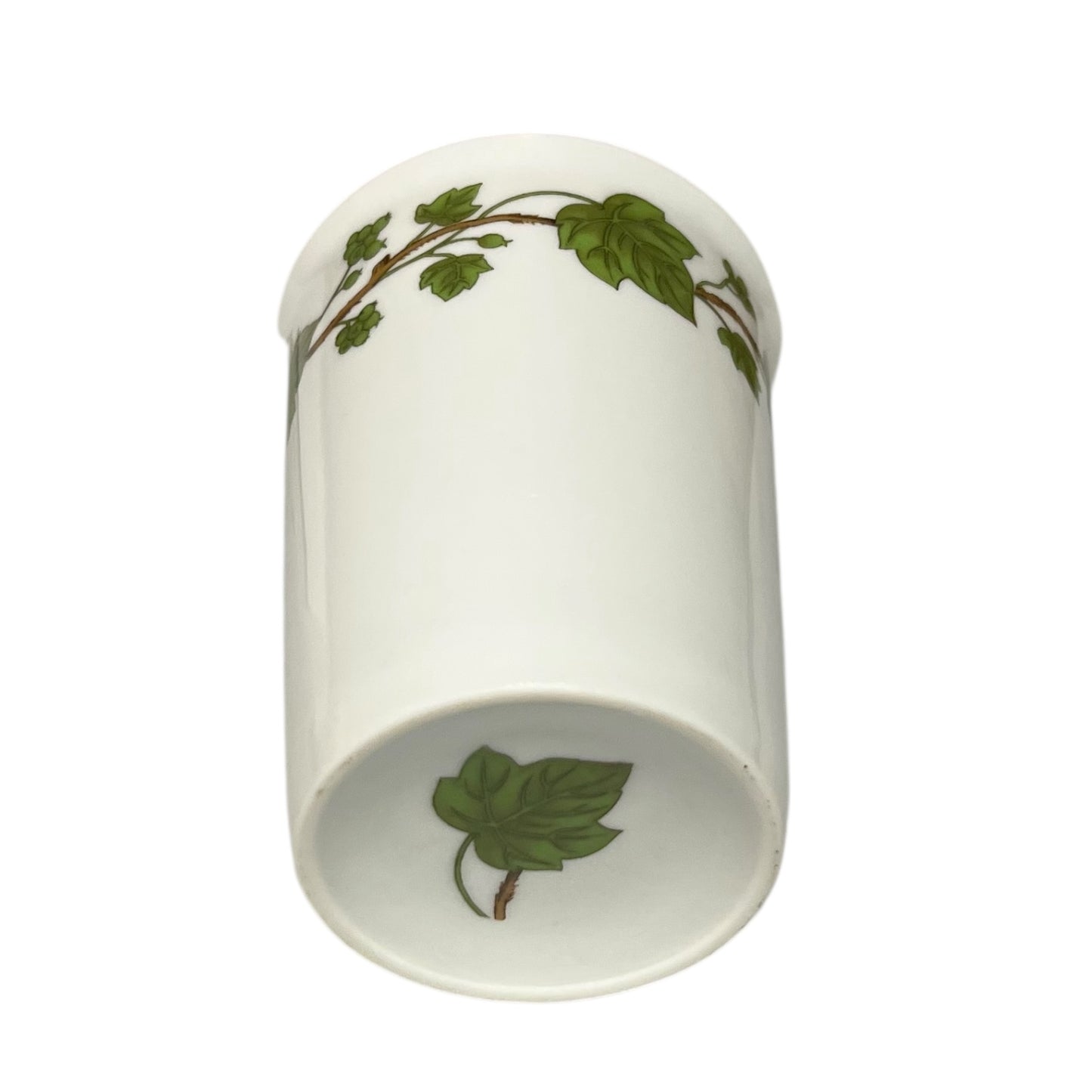 Porcelain bathroom tumbler featuring green leaf patterns on a white background