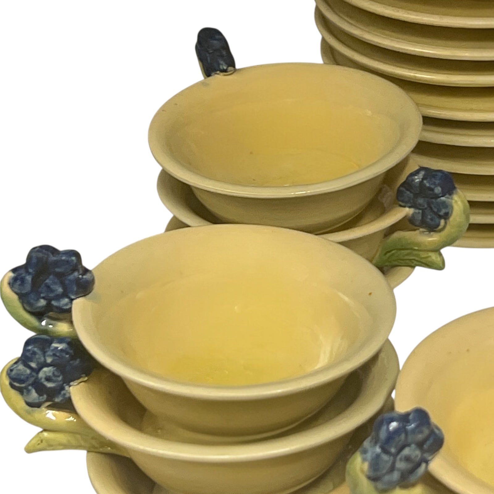 Set of yellow ceramic cups with blueberry decorations on a white background