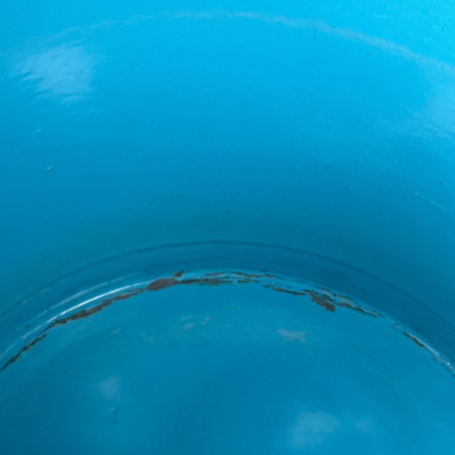 Close up of blue metal bucket with a wooden handle on a white background