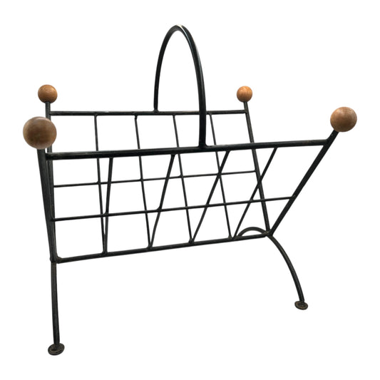 Wrought iron magazine rack with wooden knobs on a white background