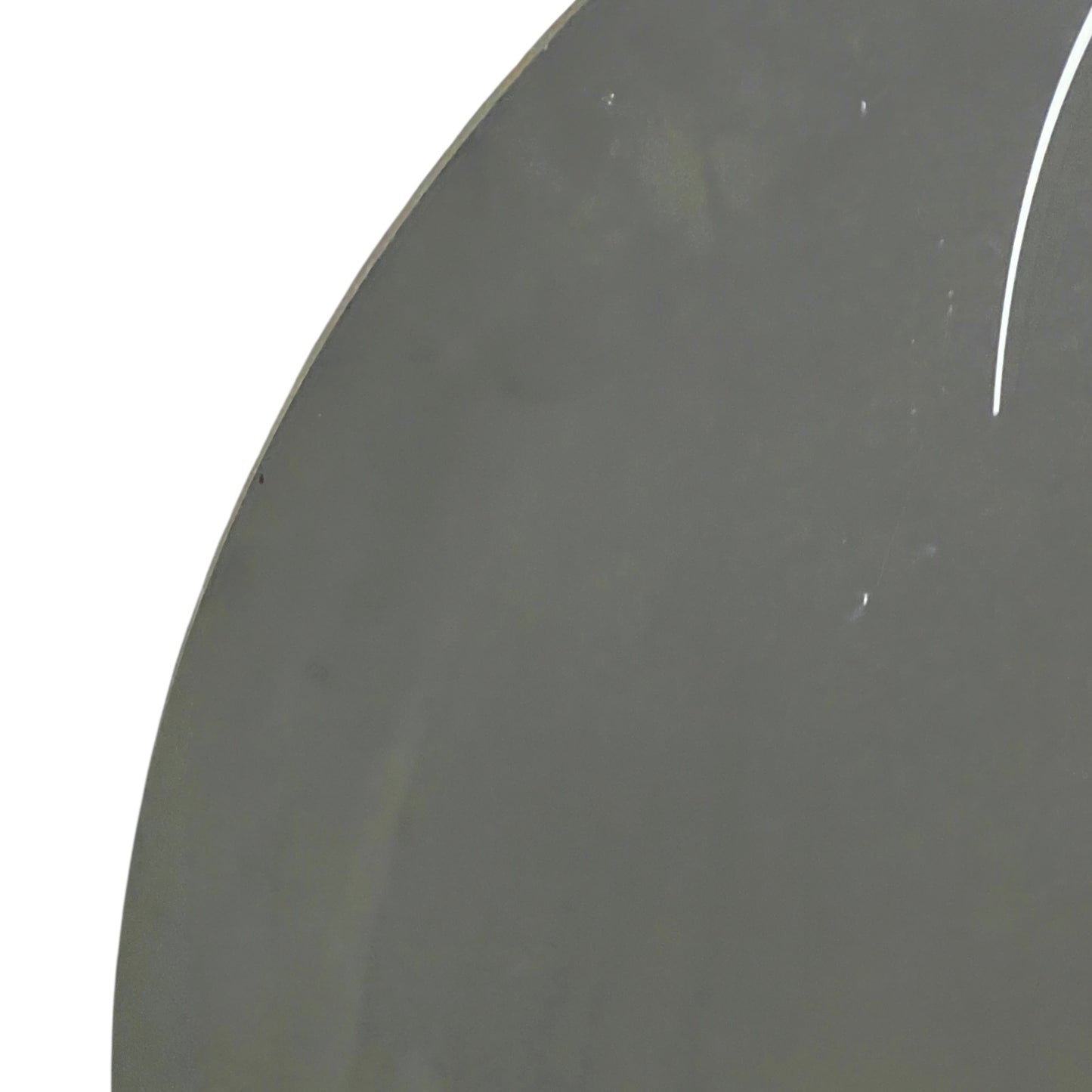 Close-up of a dark gray circular object with a white line on a white background