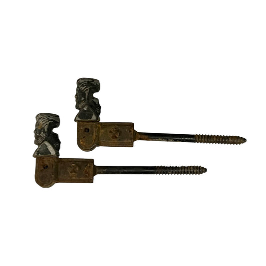 Two antique-style metal window shutter brackets with sculpted busts of men wearing turbans, shown on a plain white background.