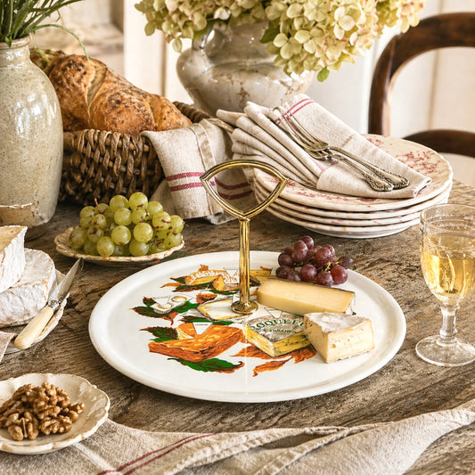 Table setting with cheese plate, bread, grapes, and wine glasses.