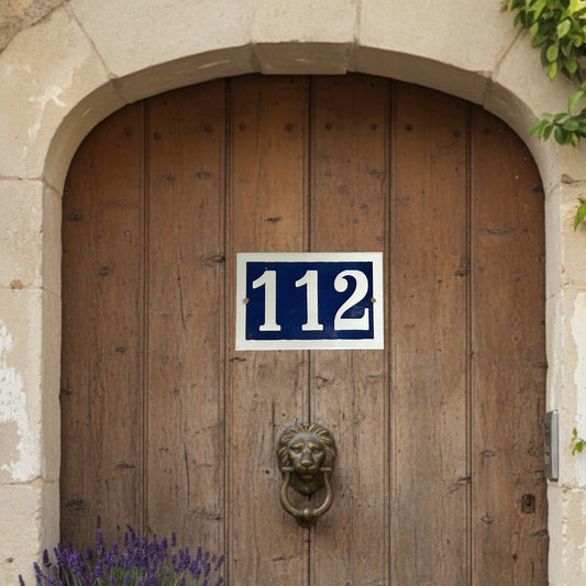 French enamel blue and white front door number 112 with a white border on a wooden door with a stone arch