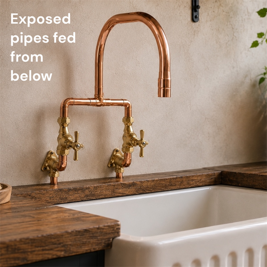 copper and brass kitchen mixer tap on a stone wall over a butler sink