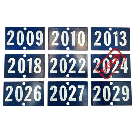 Collection of blue number plates with years printed on them, with a red stamp over '2024'.