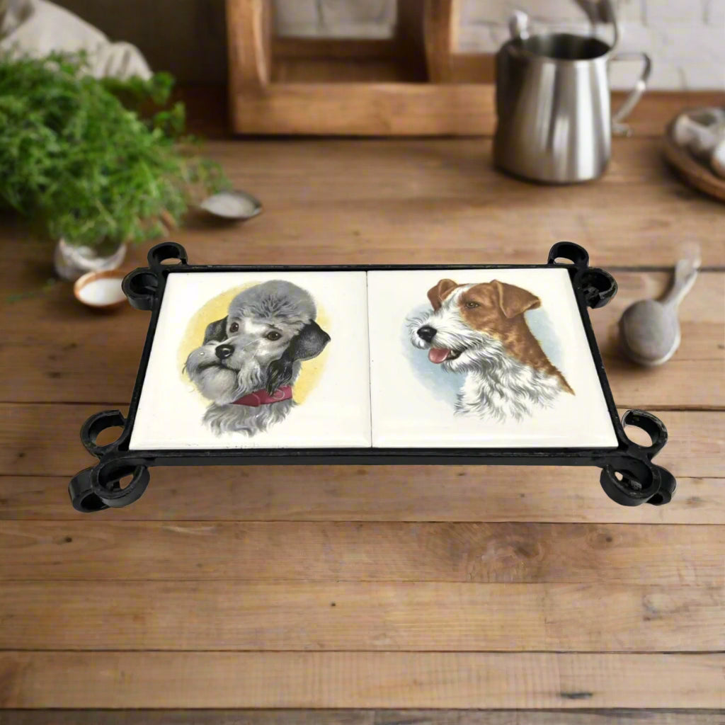 French tile topped pan trivet with an iron frame and 2 tiles -  dog pictures on a table in a kitchen with plants and ingredients