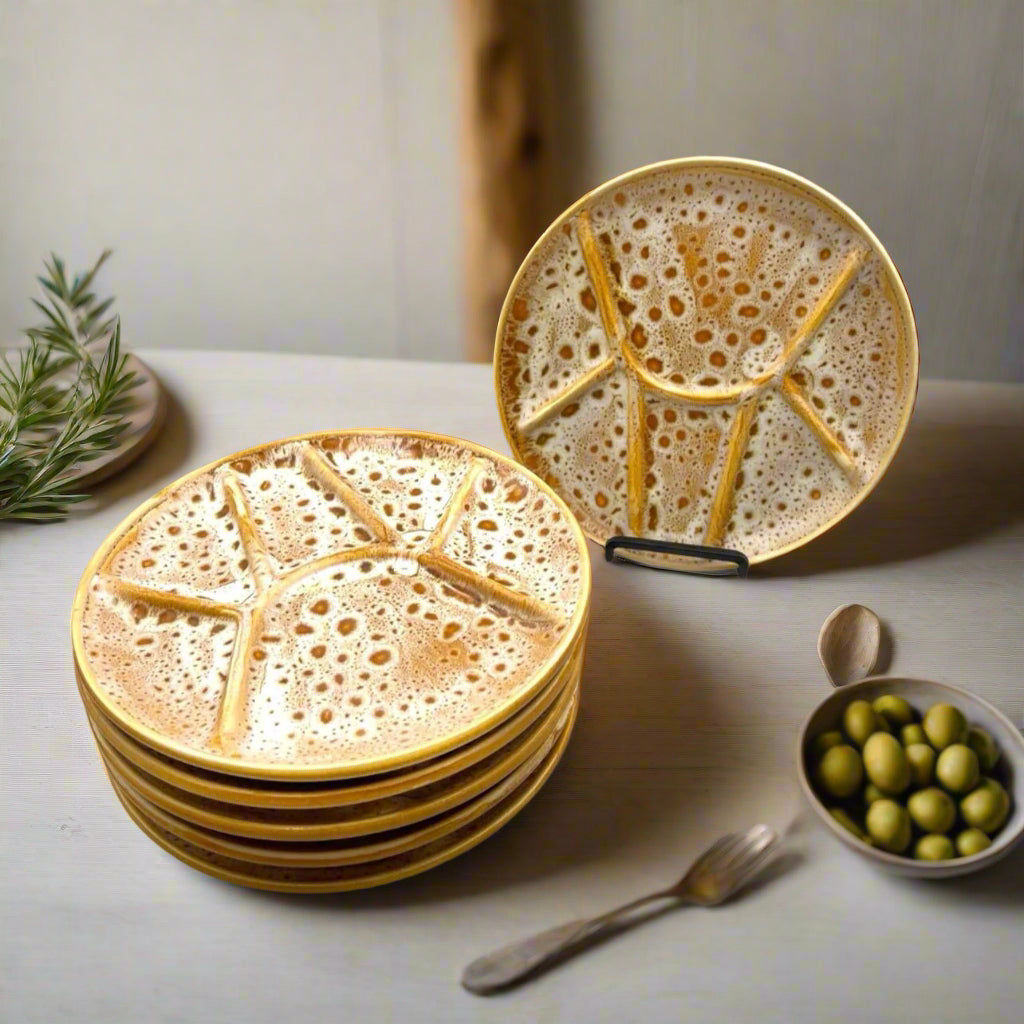Set of 6 amber and white speckled fondue plates made by Niderviller on a pale kitchen counter top with a small bowl of olives and a sprig of herbs.