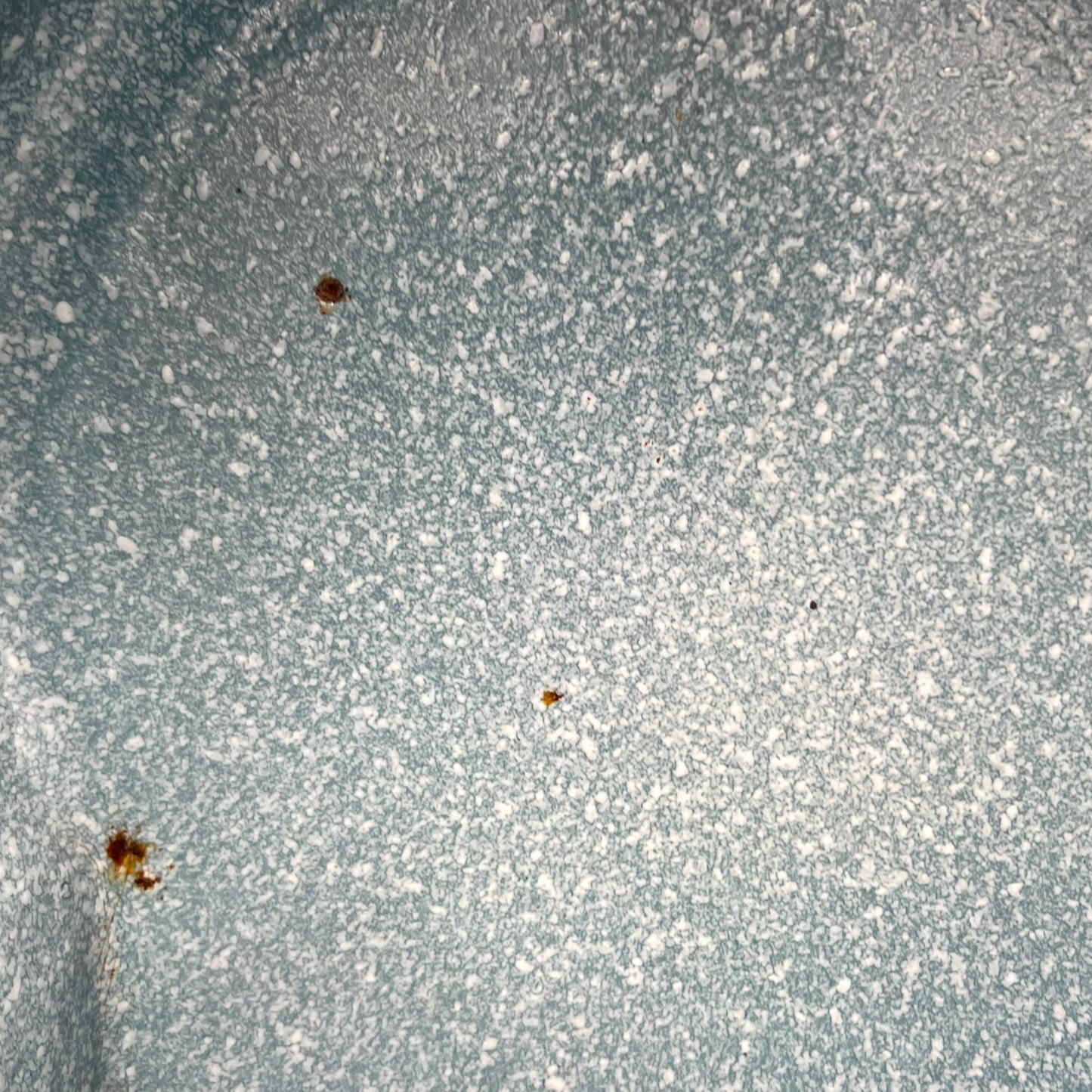 Close-up of wear and tear on a blue metal planter on a white background