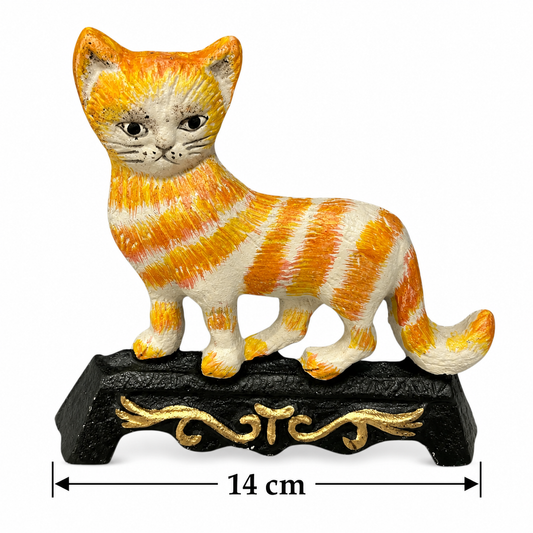 An orange and white striped cat figurine standing on a black decorative base with gold scrollwork, shown on a white background with a 14 cm width measurement marker below.