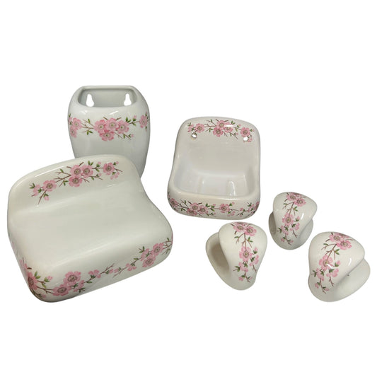 A six-piece white ceramic bathroom vanity set with a pink floral border pattern, including a sink tray, soap dish, pedestal sink, and three cabinet knobs, shown on a white background.
