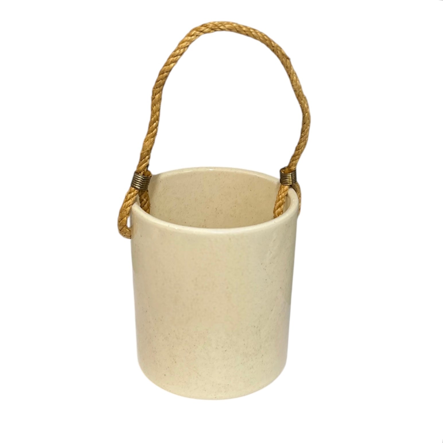 A small cylindrical kitchen pot  in a warm cream-colored textured material, featuring a natural tan rope handle with brass-coloured metal hardware, shown against a plain white background.