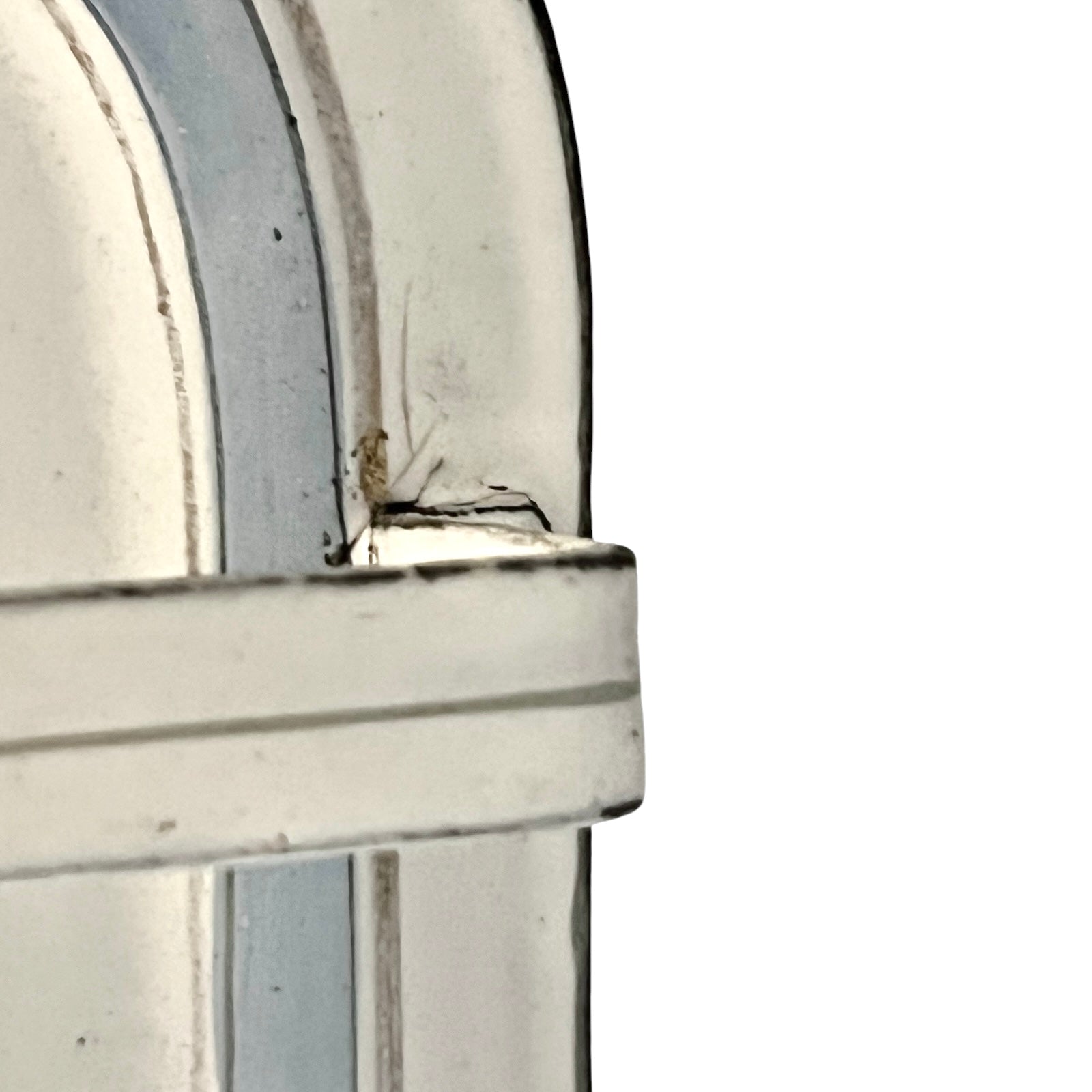 Close-up of an enamel drip tray with a scuff on the curved edge against a white background.