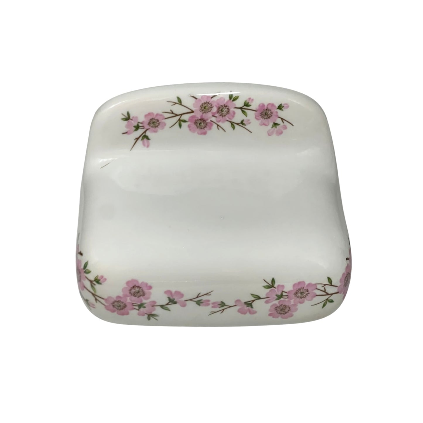 A square white ceramic dish with rounded corners, decorated with delicate pink floral branches along the top and bottom edges, shown against a plain white background.