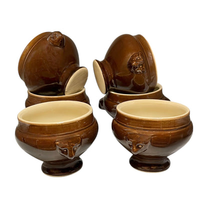 Set of six brown ceramic soup bowls with lion head handle designs on a white background