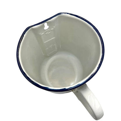 Inside view of white enamel jug with blue rim and spout on a white background