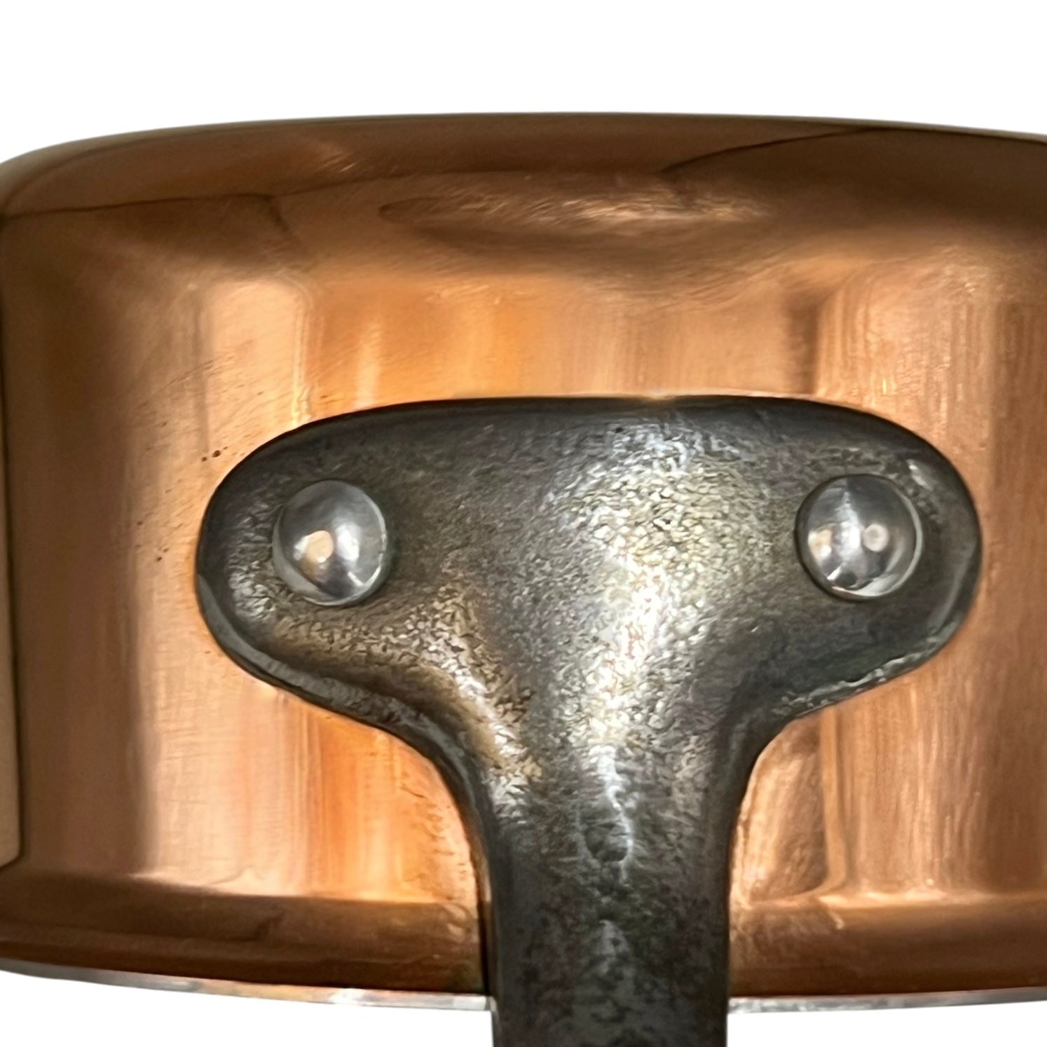 close up of the metal handle of a copper pan
