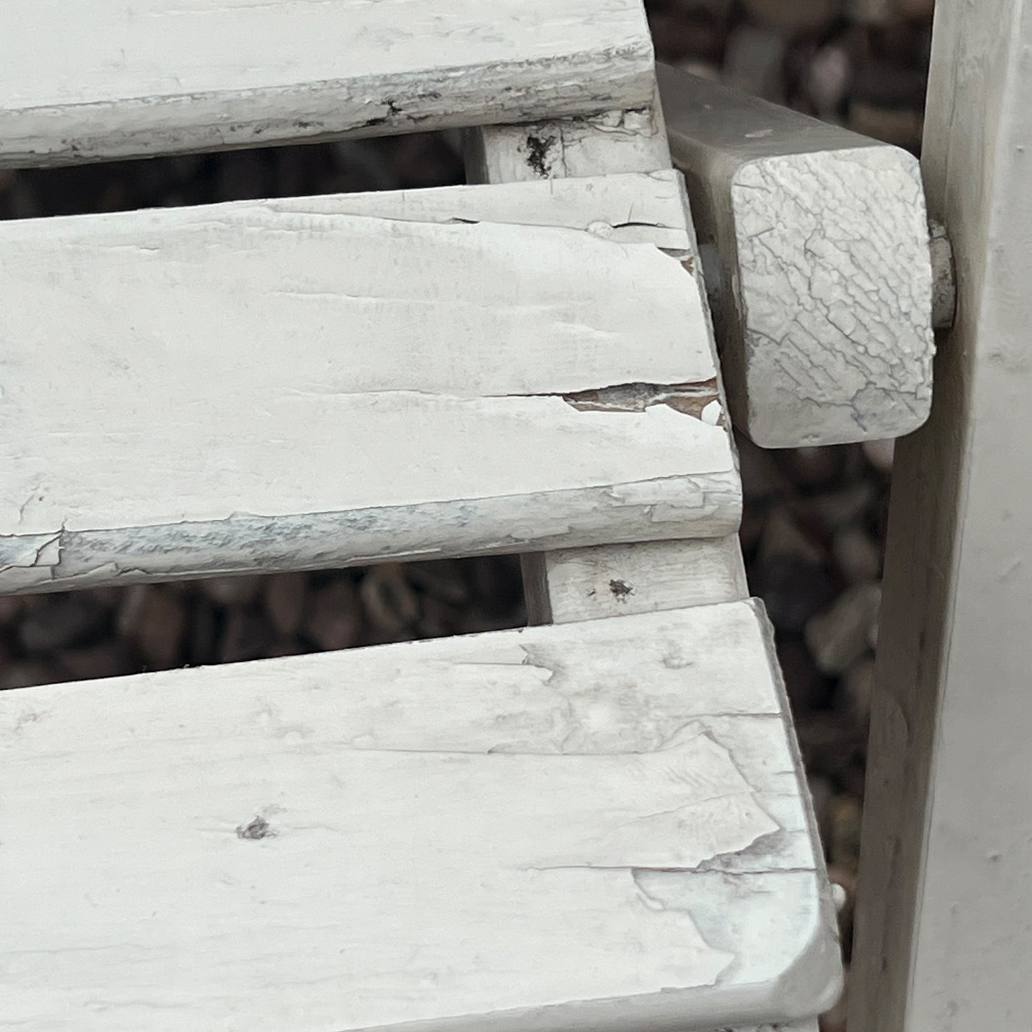A close-up view of a painted wooden slatted garden chair set amidst a lush garden backdrop.